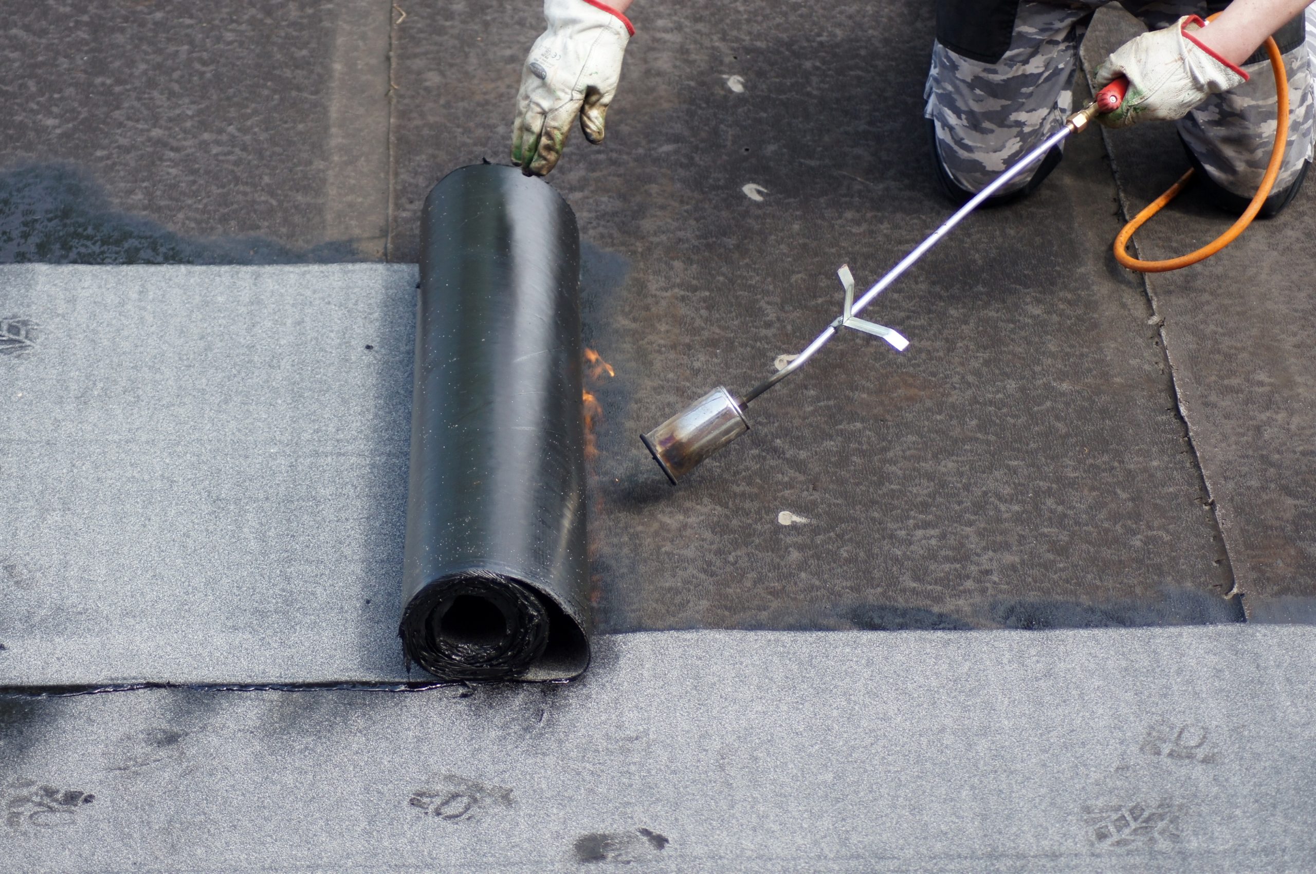 Roofer applying bitumen roofing felt with blow torch Roofer applying bitumen roofing felt with blow torch