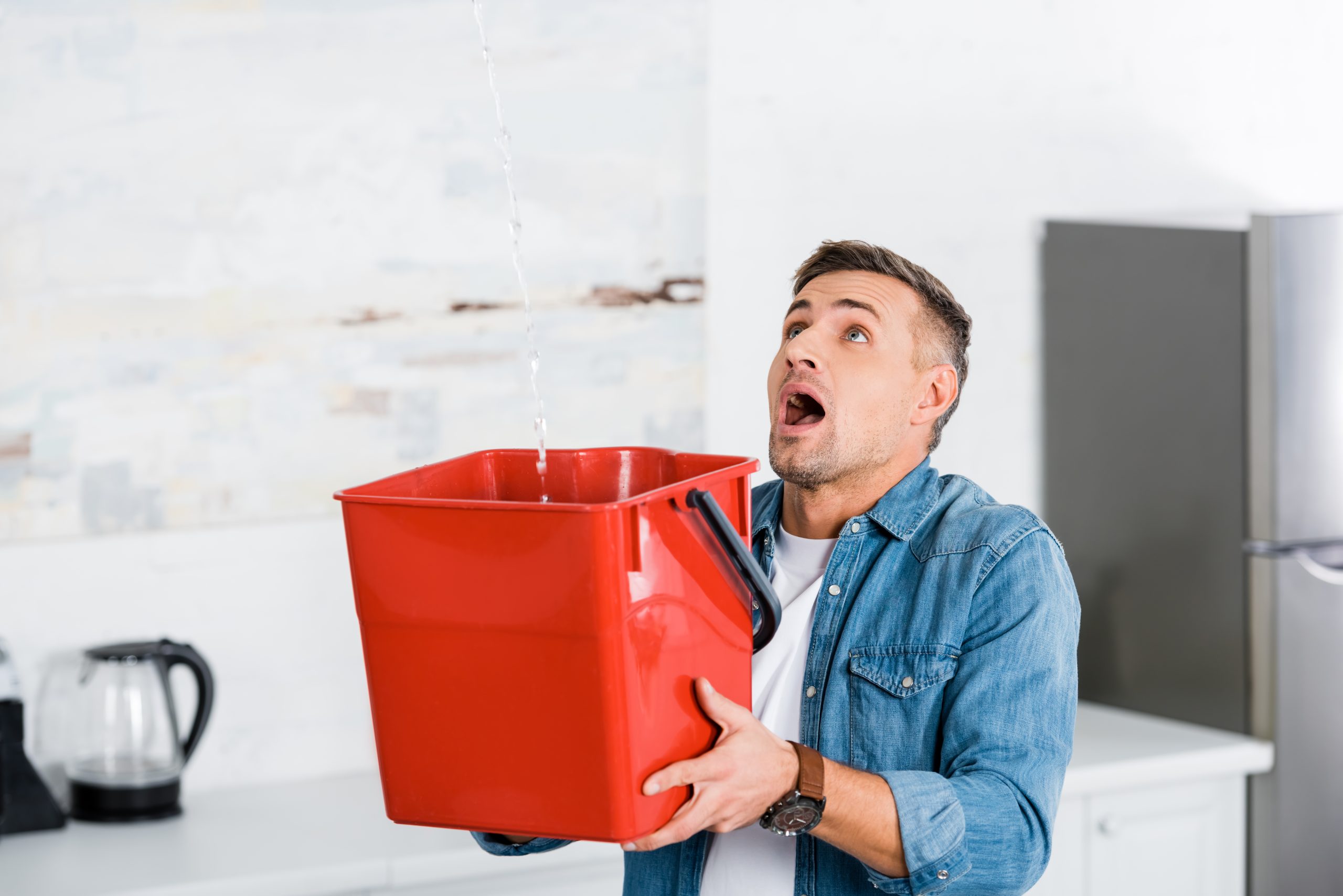 Man holding bucket catching water from roof leak Man holding bucket catching water from roof leak